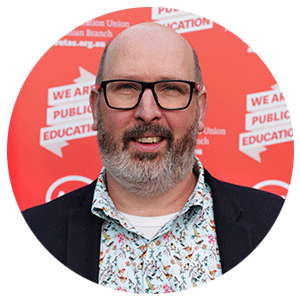 Image of bearded man wearing glasses and a colourful shirt.
